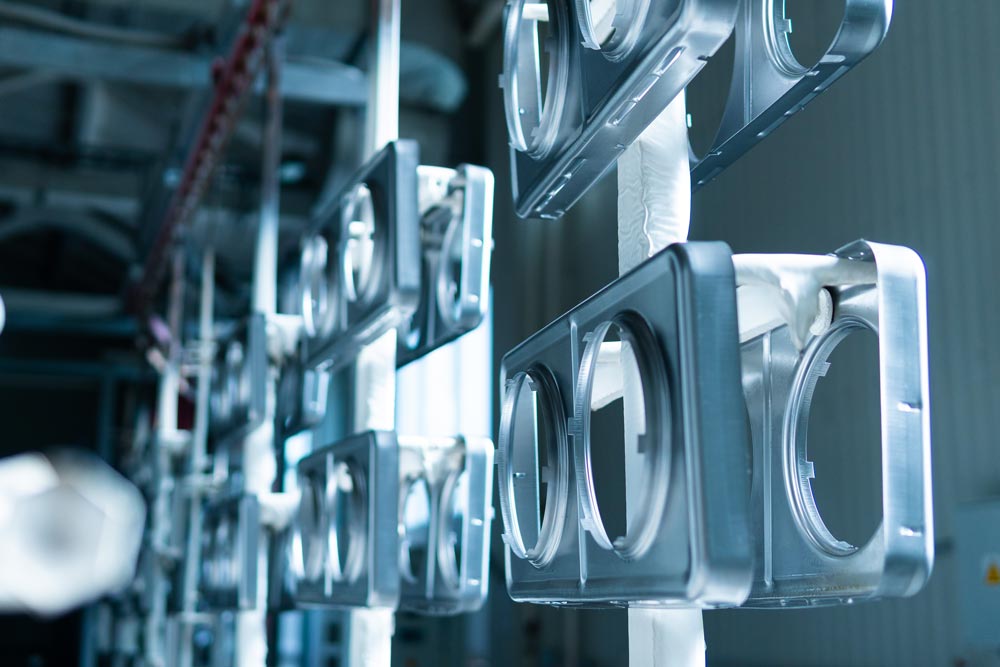 Metalldetaljer som hänger på krokar för att pulverlackeras